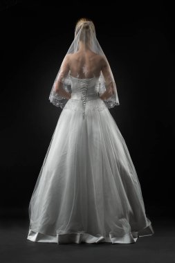 Uzun, güzel, beyaz bir gelinlik ve dantelli bir duvak içinde gelin. Siyah arkaplan