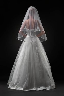 Uzun, güzel, beyaz bir gelinlik ve dantelli bir duvak içinde gelin. Siyah arkaplan