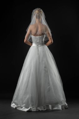 Uzun, güzel, beyaz bir gelinlik ve dantelli bir duvak içinde gelin. Siyah arkaplan