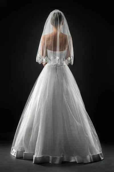 Uzun, güzel, beyaz bir gelinlik ve dantelli bir duvak içinde gelin. Siyah arkaplan