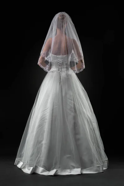 Uzun, güzel, beyaz bir gelinlik ve dantelli bir duvak içinde gelin. Siyah arkaplan