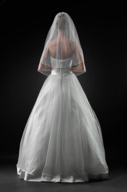 Uzun, güzel, beyaz bir gelinlik ve dantelli bir duvak içinde gelin. Siyah arkaplan