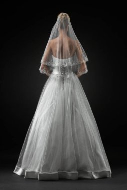 Uzun, güzel, beyaz bir gelinlik ve dantelli bir duvak içinde gelin. Siyah arkaplan