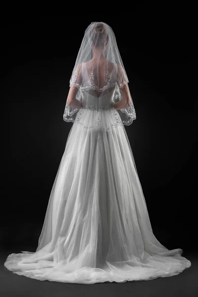 Uzun, güzel, beyaz bir gelinlik ve dantelli bir duvak içinde gelin. Siyah arkaplan