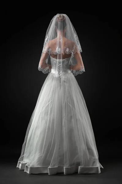 Uzun, güzel, beyaz bir gelinlik ve dantelli bir duvak içinde gelin. Siyah arkaplan