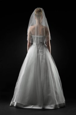 Uzun, güzel, beyaz bir gelinlik ve dantelli bir duvak içinde gelin. Siyah arkaplan