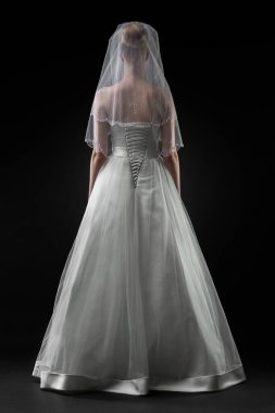 Uzun, güzel, beyaz bir gelinlik ve dantelli bir duvak içinde gelin. Siyah arkaplan