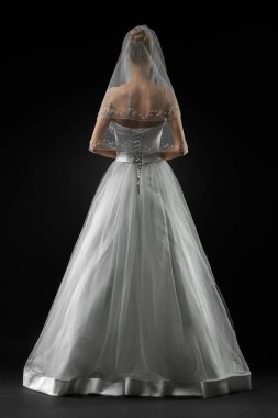 Uzun, güzel, beyaz bir gelinlik ve dantelli bir duvak içinde gelin. Siyah arkaplan