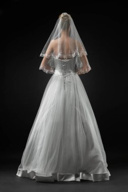Uzun, güzel, beyaz bir gelinlik ve dantelli bir duvak içinde gelin. Siyah arkaplan