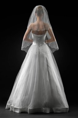 Uzun, güzel, beyaz bir gelinlik ve dantelli bir duvak içinde gelin. Siyah arkaplan