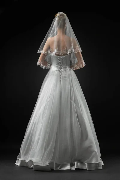 Uzun, güzel, beyaz bir gelinlik ve dantelli bir duvak içinde gelin. Siyah arkaplan