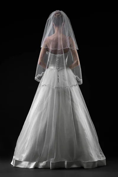 Uzun, güzel, beyaz bir gelinlik ve dantelli bir duvak içinde gelin. Siyah arkaplan