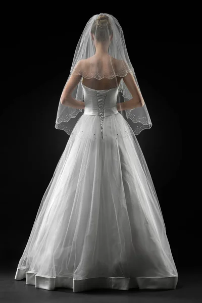 Uzun, güzel, beyaz bir gelinlik ve dantelli bir duvak içinde gelin. Siyah arkaplan