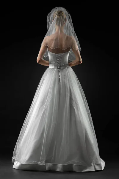 Uzun, güzel, beyaz bir gelinlik ve dantelli bir duvak içinde gelin. Siyah arkaplan