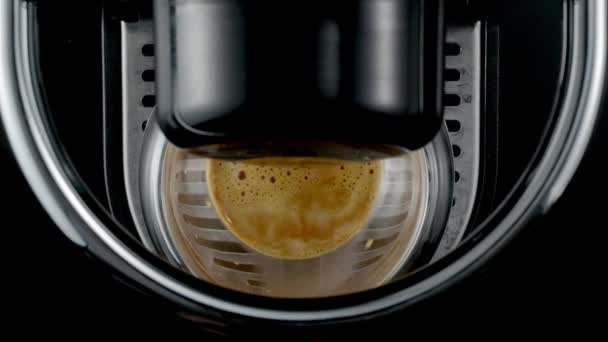 光沢のある金属の詳細を持つブラックコーヒーマシンは ガラスカップに新鮮な熱い飲み物を注ぎます 黒を基調としたコーヒー作りのプロセス トップ表示 — ストック動画