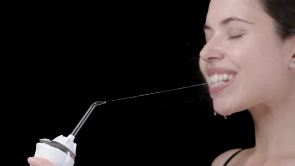 Молода жінка чистить зуби за допомогою іригатора — стокове відео
