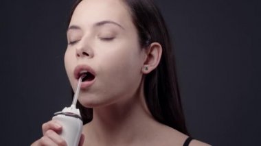 Banyoda dişlerini temizleyen genç bir kadın.