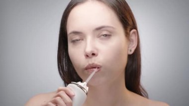 Uzun saçlı bir kadın, su temizleyicisiyle dişlerini temizliyor.