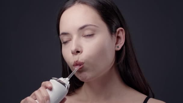 Dişlerini su temizleyicisiyle temizleyen genç bir kadın — Stok video