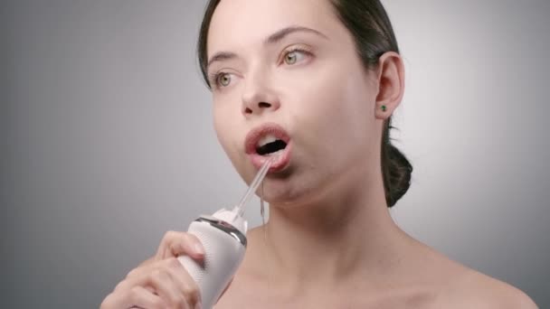 Молодая женщина чистит зубы зубной нитью и улыбается — стоковое видео
