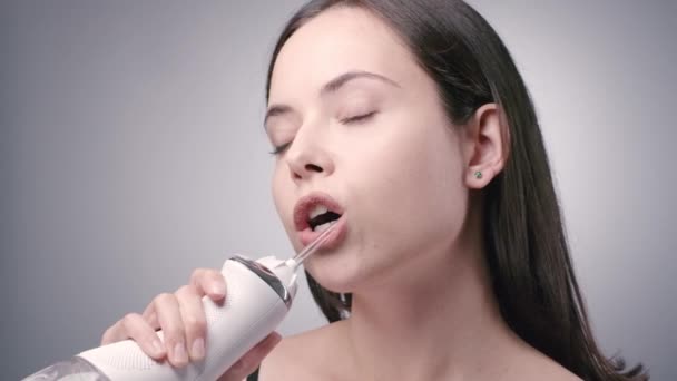 Jeune femme avec de longues dents de nettoyage des cheveux foncés avec un flotteur d'eau — Video