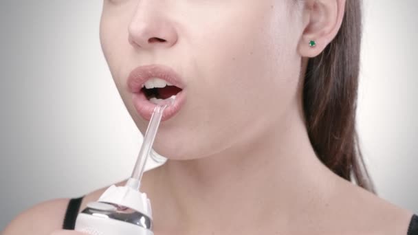 Koyu renk saçlı, dişlerini temizleyen, ağız sulandırıcı kullanan genç bir kadın. — Stok video