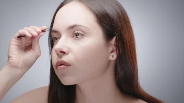 Жінка виправляє брови пінцетом — стокове відео
