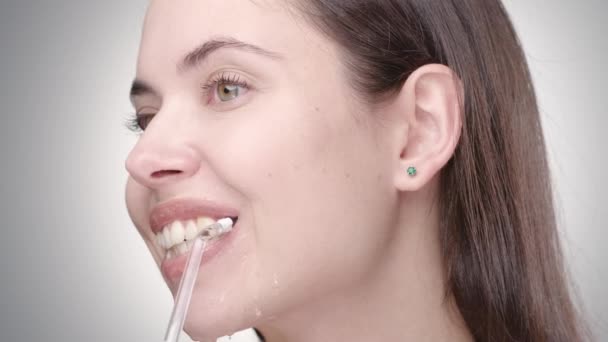 Kvinna med naken makeup rengöring tänder med bevattnare — Stockvideo