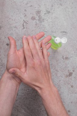 Gri arka planda avuçlar ve sıhhi temizleyici