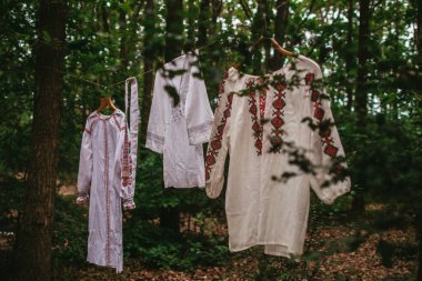 Beyaz Ukrayna ulusal nakışlı gömlekler ormanda bir ipe asılı.