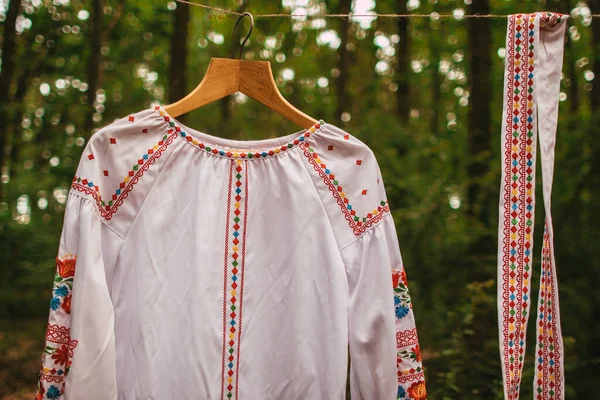 在森林的衣架上 白色的乌克兰民族绣花衣服和腰带 — 图库照片