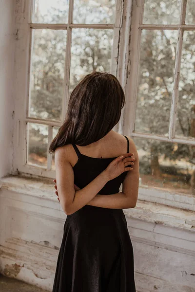 Uma Menina Está Vestido Preto Perto Janela Segura Suas Mãos — Fotografia de Stock