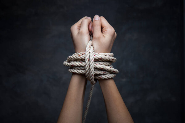 Hands of a victim woman tied up with rope 