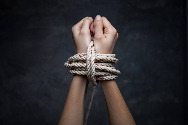 Hands of a missing victim woman tied up with rope 