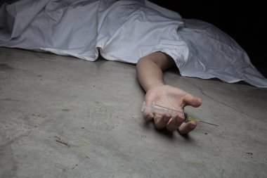 Yerdeki cesedin elinde ilaçların yakın çekim. Arka planda, Genç uyuşturucu bağımlısı