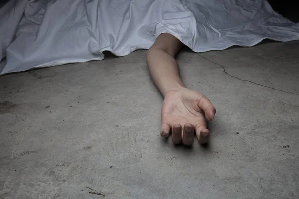 The dead woman's body. Focus on hand