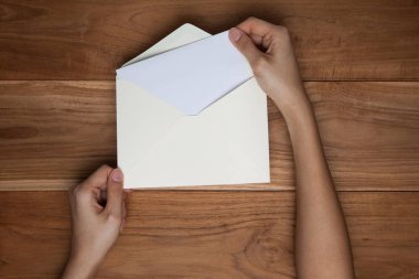 Ahşap masa, stüdyoda üstten görünüm üzerinde bir el tutmak bir zarf ve kartpostal.