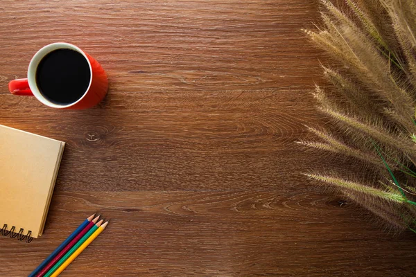 Werkruimte met gras, notebook, koffie, potloden op tafel — Stockfoto