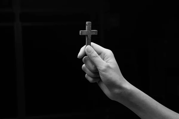 Handen met kruis op een zwarte achtergrond — Stockfoto