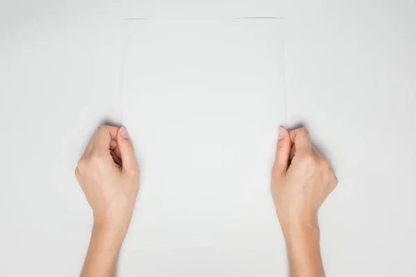Une main féminine tient un papier blanc vide isolé en blanc — Photo