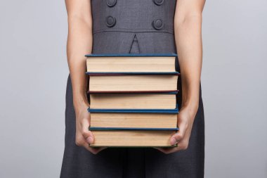 Ofiste bir yığın kitap taşıyan bir kadın.