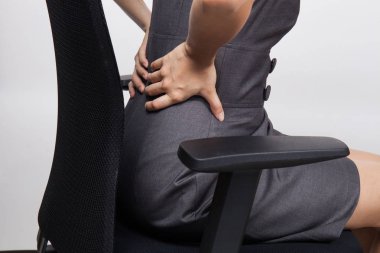 Ofis masasında otururken sırtı ağrıyan genç iş kadını