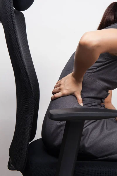 Young businesswoman having back pain while sitting at office des — Stock Photo, Image