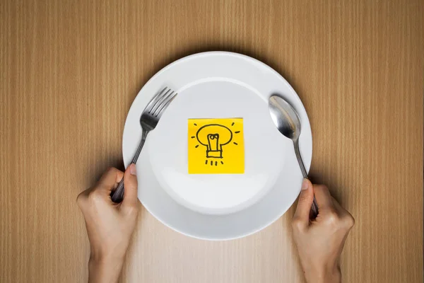 idea note in plate and fork and spoon on wooden table. brain food Idea concept