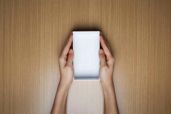 Eine weibliche Hand hält eine leere (leere) weiße Schachtel auf dem Schreibtisch( — Stockfoto