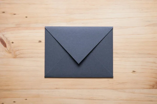 A grey envelope on the wood desk, top view at the studio. — Stock Photo, Image
