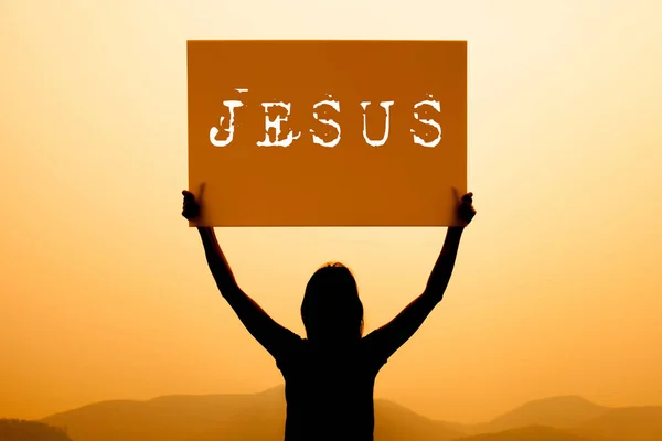 Silhouette of woman holding a Jesus sign on top mountain — Stock Photo, Image
