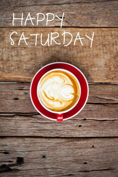 Feliz sábado palabra en la taza roja de café en la mesa de madera — Foto de Stock