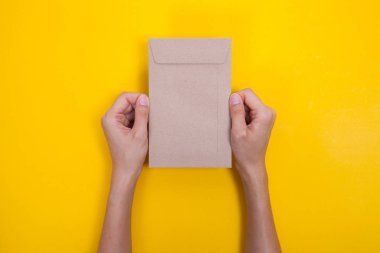 el sarı masada bir zarf ve kartpostal tutun