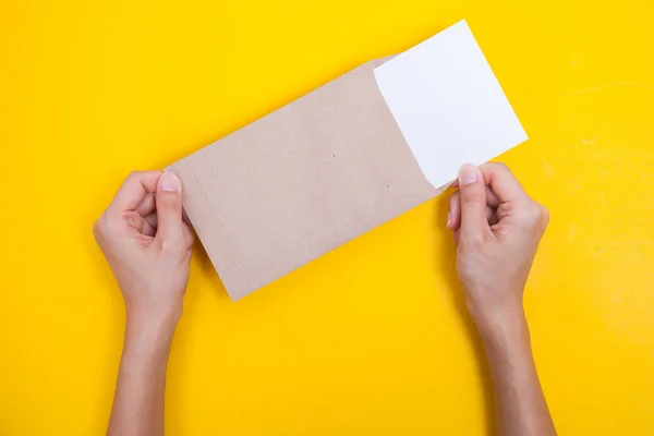 Mão segurar um envelope e cartão postal na mesa amarela — Fotografia de Stock